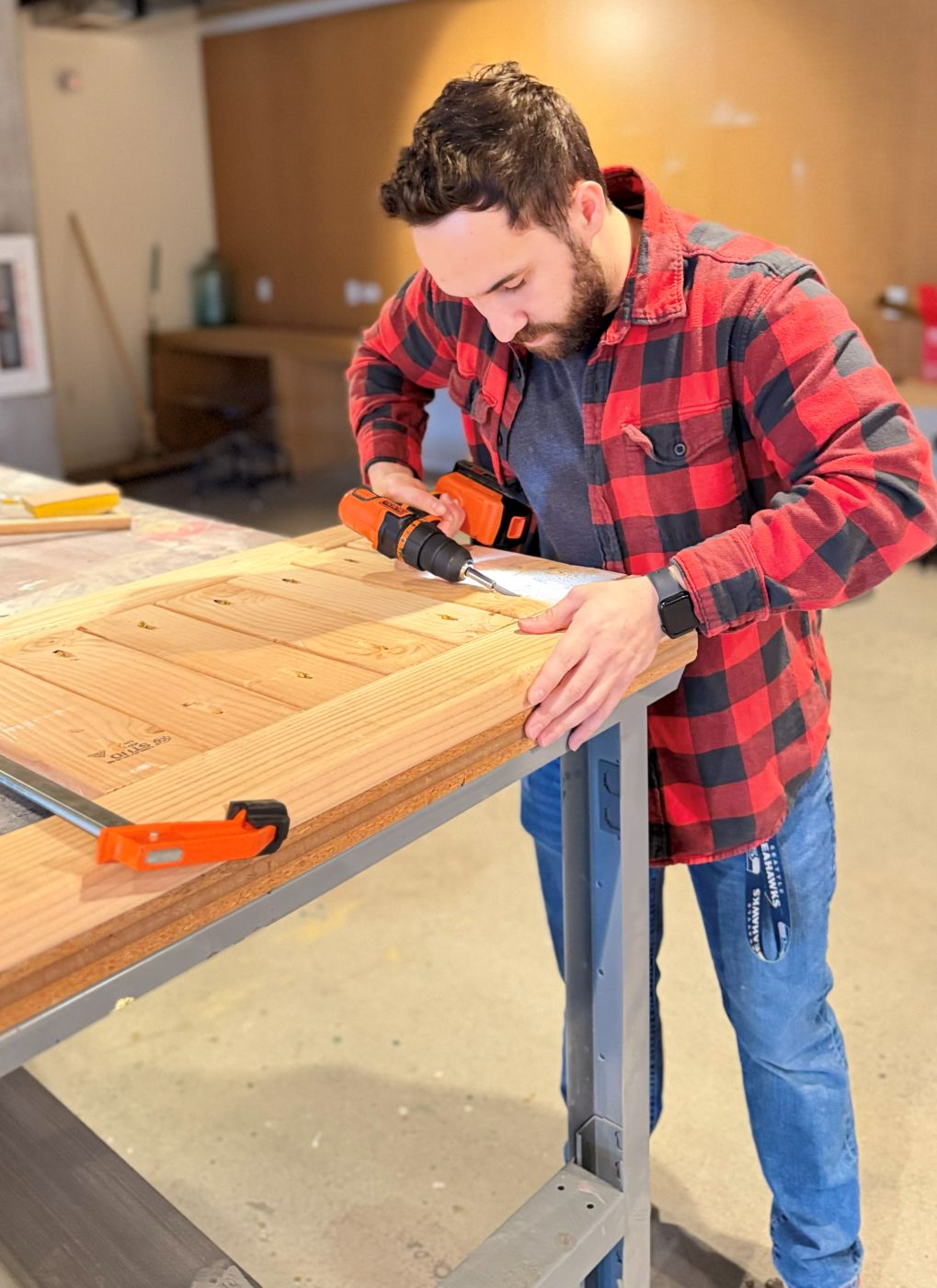 Assembling a planter side panel at the workbench, driving a screw with a cordless drill while the slats are clamped down.